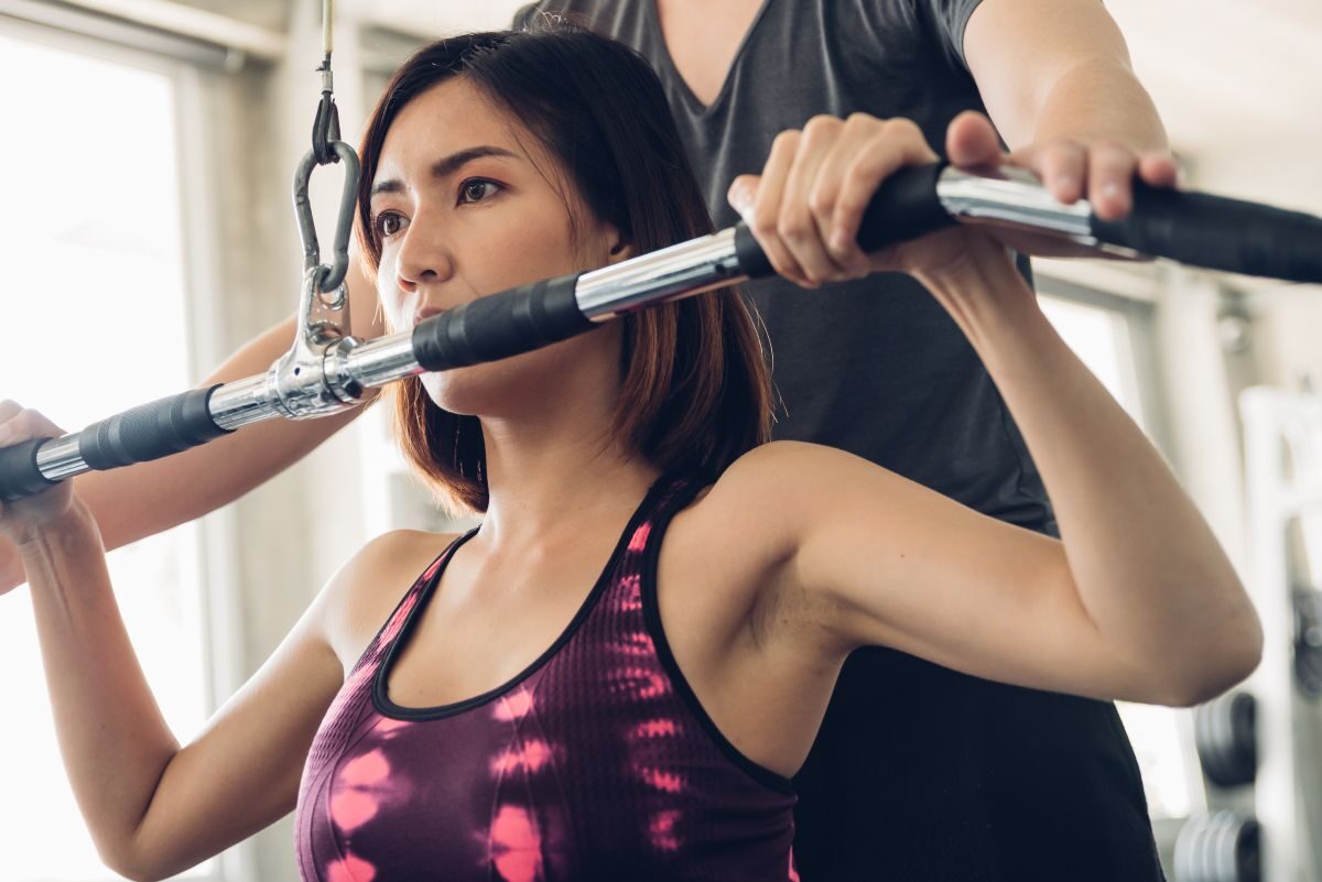 mujer haciendo rutina de ejercicios asesorada por su personal trainer